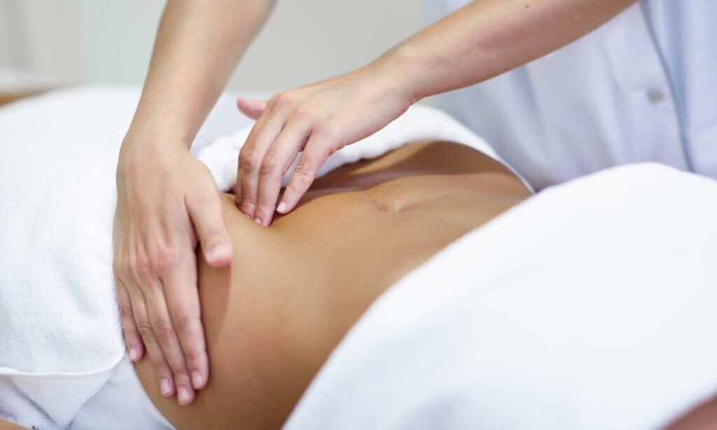 Female patient is receiving treatment by professional osteopathy therapist. Woman receiving a belly massage at spa salon